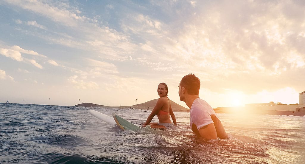 Couple surfs in the ocean together, their relationship strong from couples counseling.